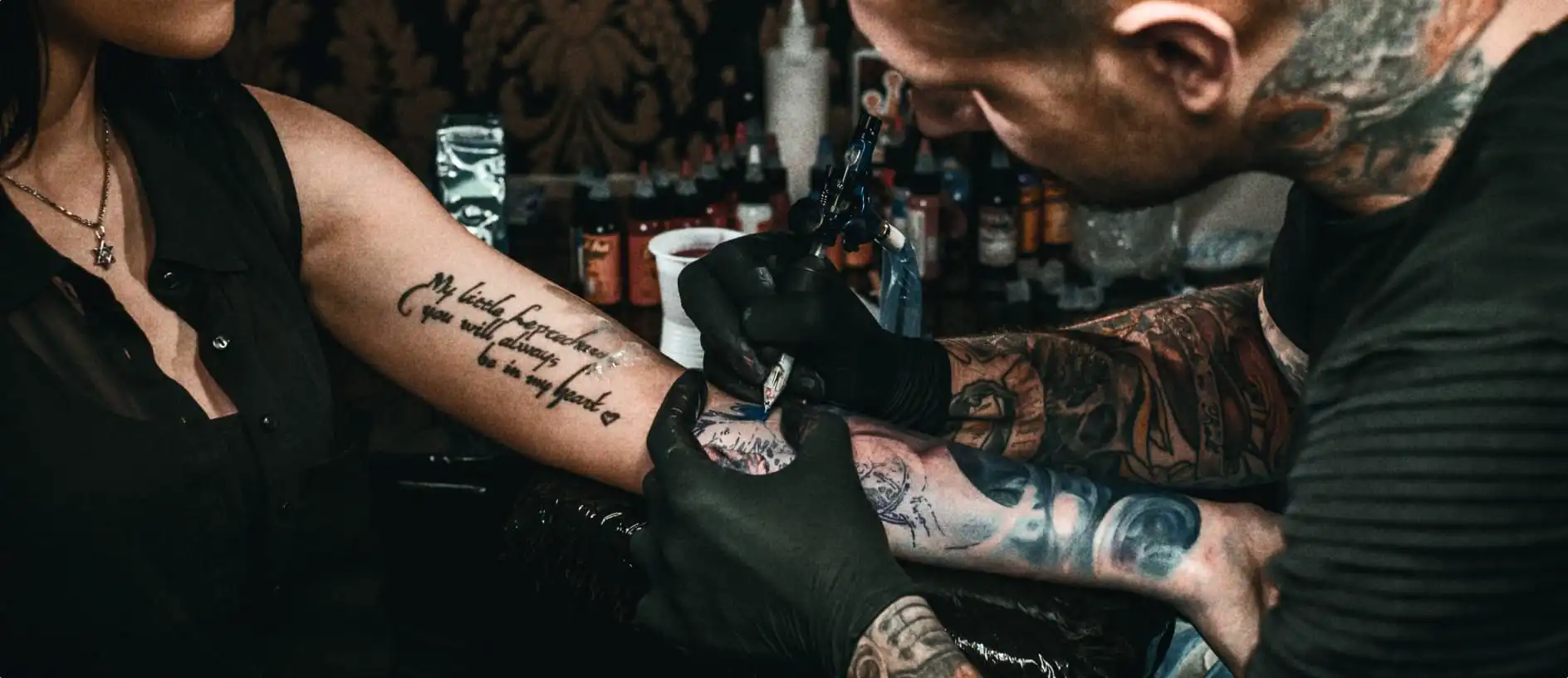 tattoo artists tattooing arm
